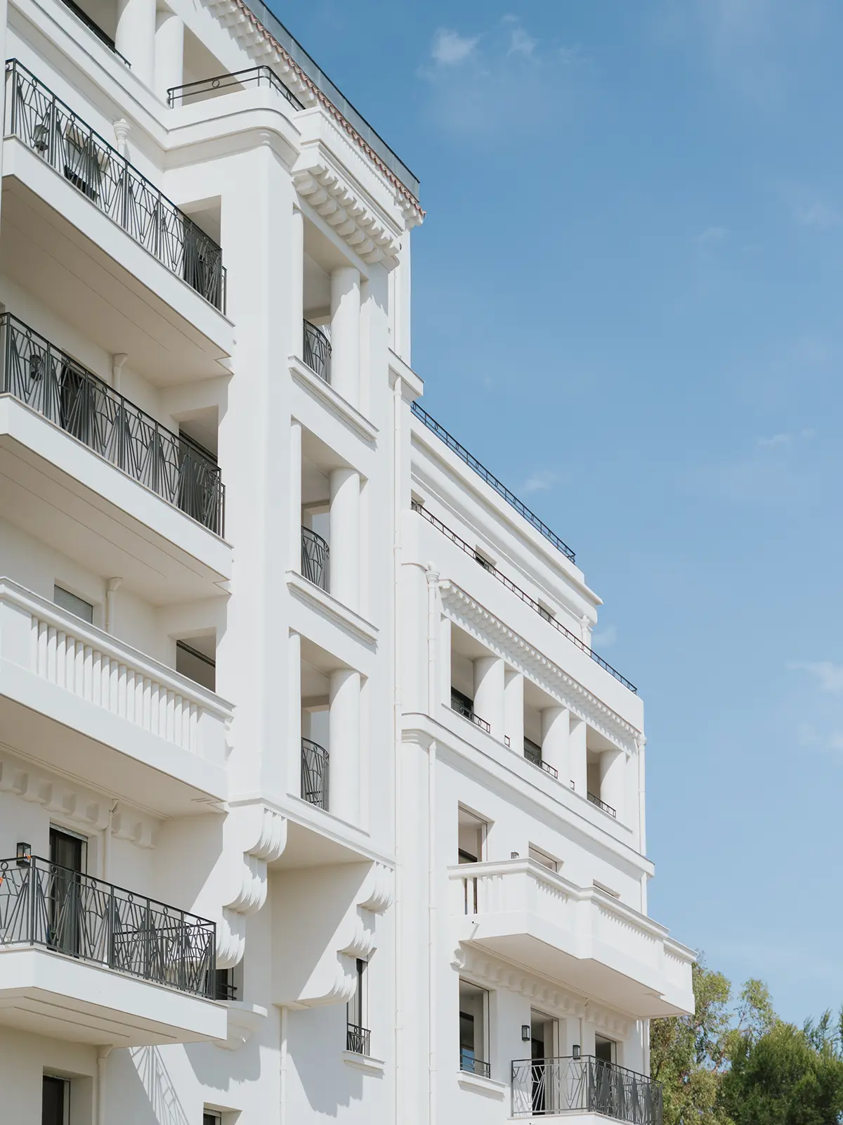Elegant white building with balconies, featuring classical design and decorative railings. Clear blue sky background enhances the structure's architectural beauty and serene surroundings.
